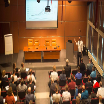 Speaker presenting in business conference room with projector and AV setup for corporate event